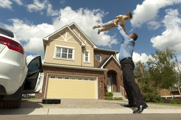 Father and son in front of their new suburban house